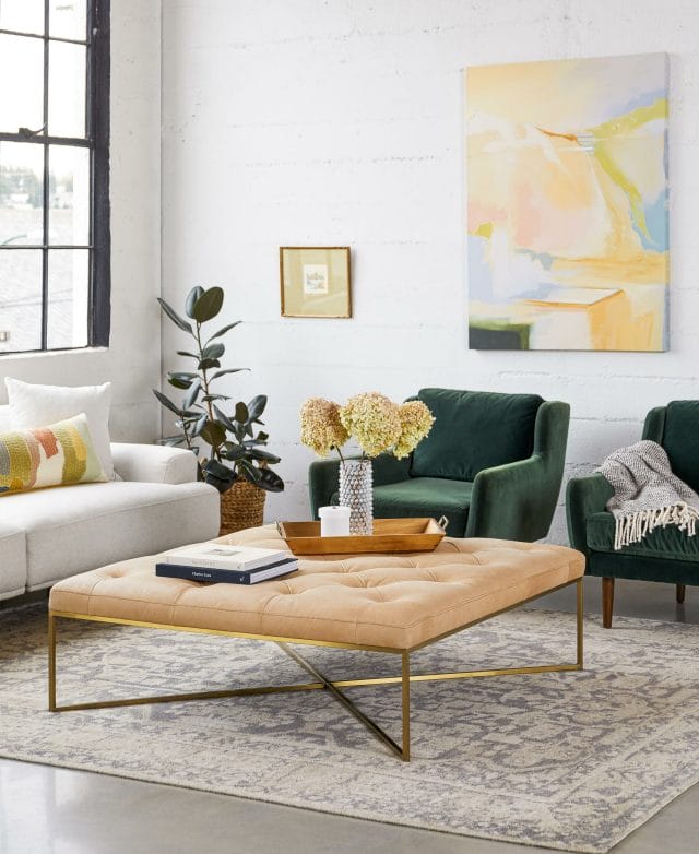 Green velvet armchairs and a sofa make up a modern living room.