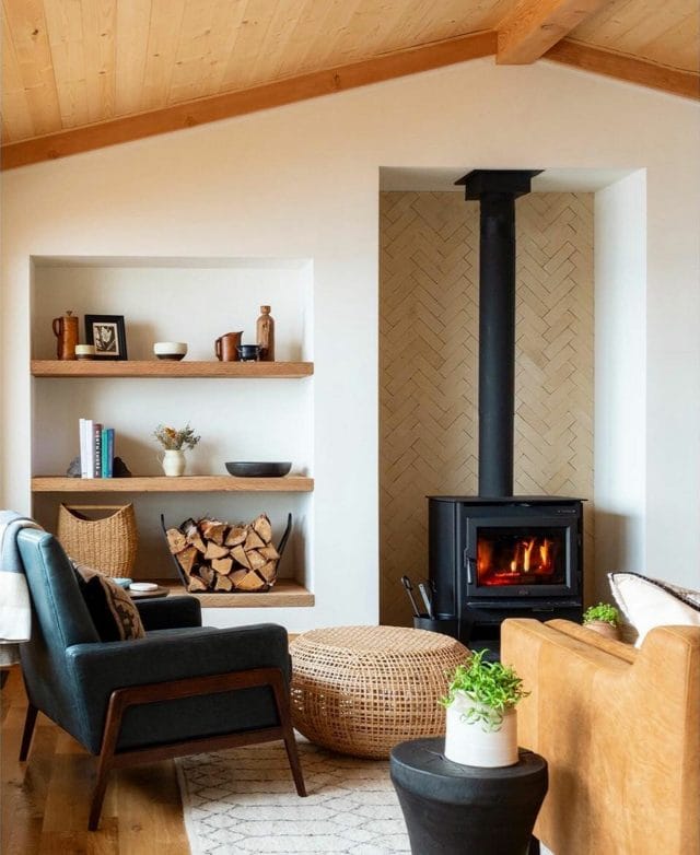 Two armchairs are turned towards a black fireplace in a cozy living room.