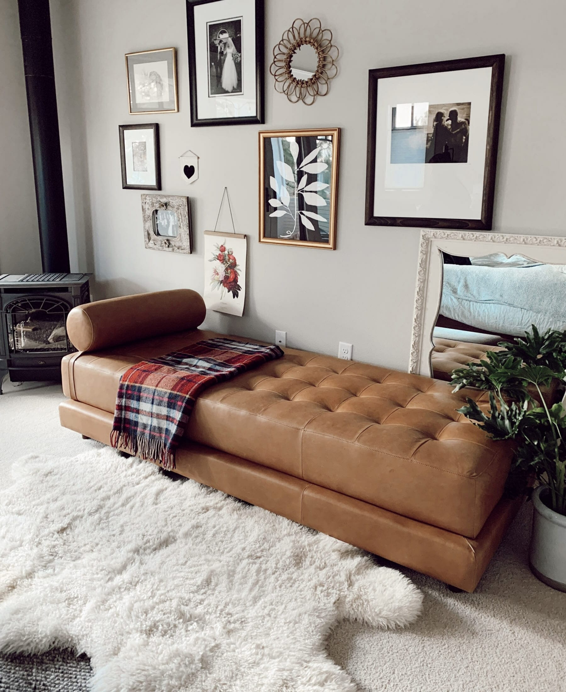 A brown leather daybed sitting beside a fluffy white throw rug.