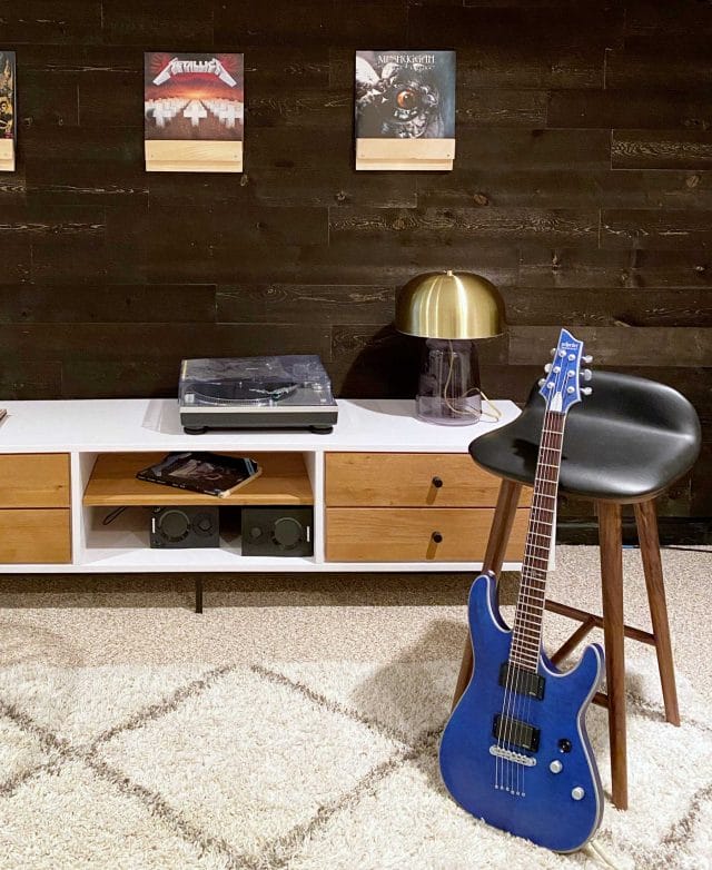 Brown and white coffee table with drawers, in front of a blue electric guitar. 