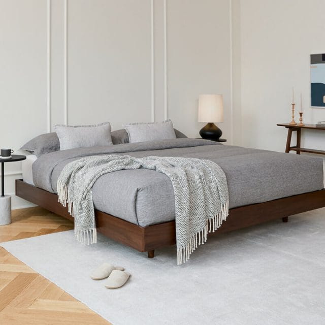 A brown walnut bedframe in a modern bedroom