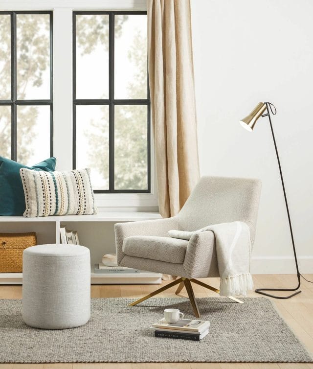 Uma cadeira giratória branca sobre um tapete cinza em uma sala de estar moderna.
