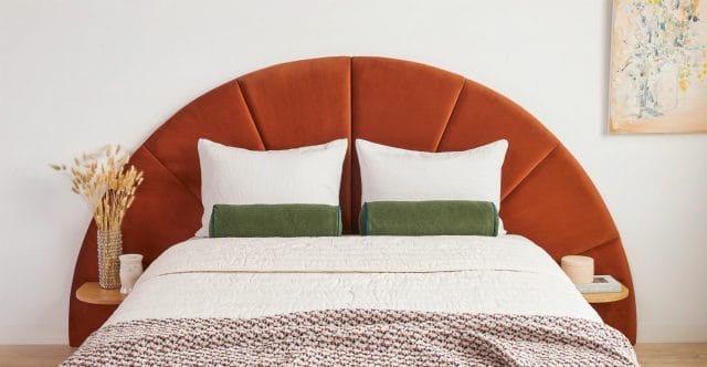 An orange velvet headboard in a mid century modern bed. 