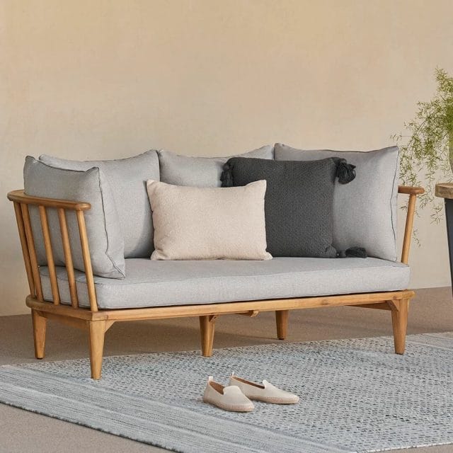 Gray and wood outdoor loveseat on a blue rug.